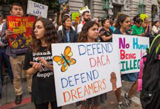 Photo of protestors holding signs that say "Defend DACA"